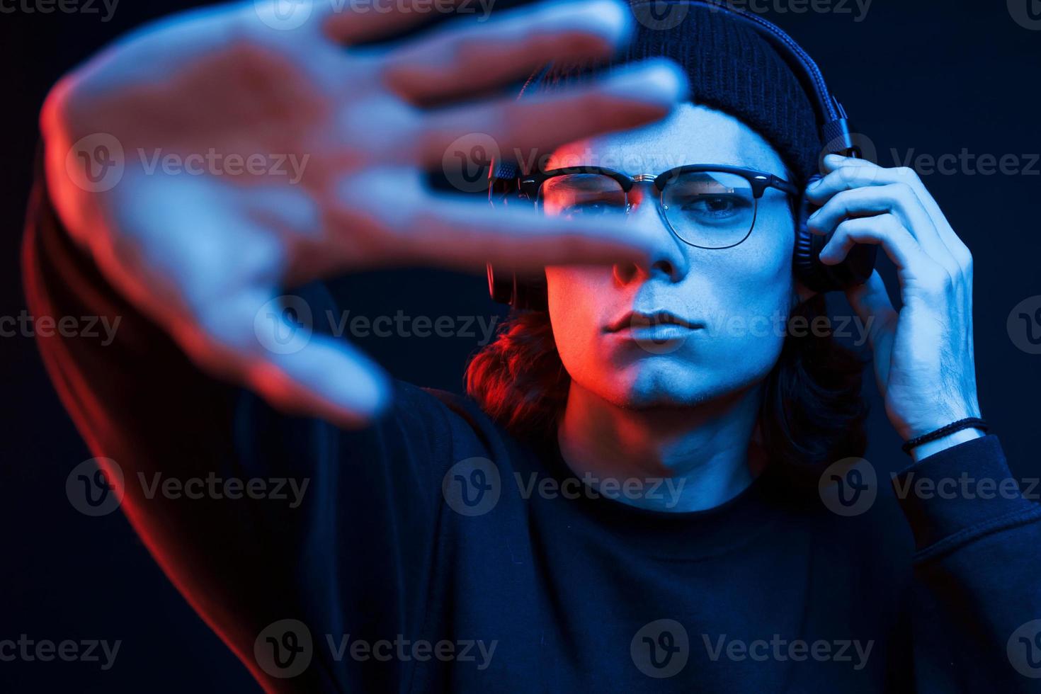 In my own world with music. Studio shot in dark studio with neon light. Portrait of serious man photo