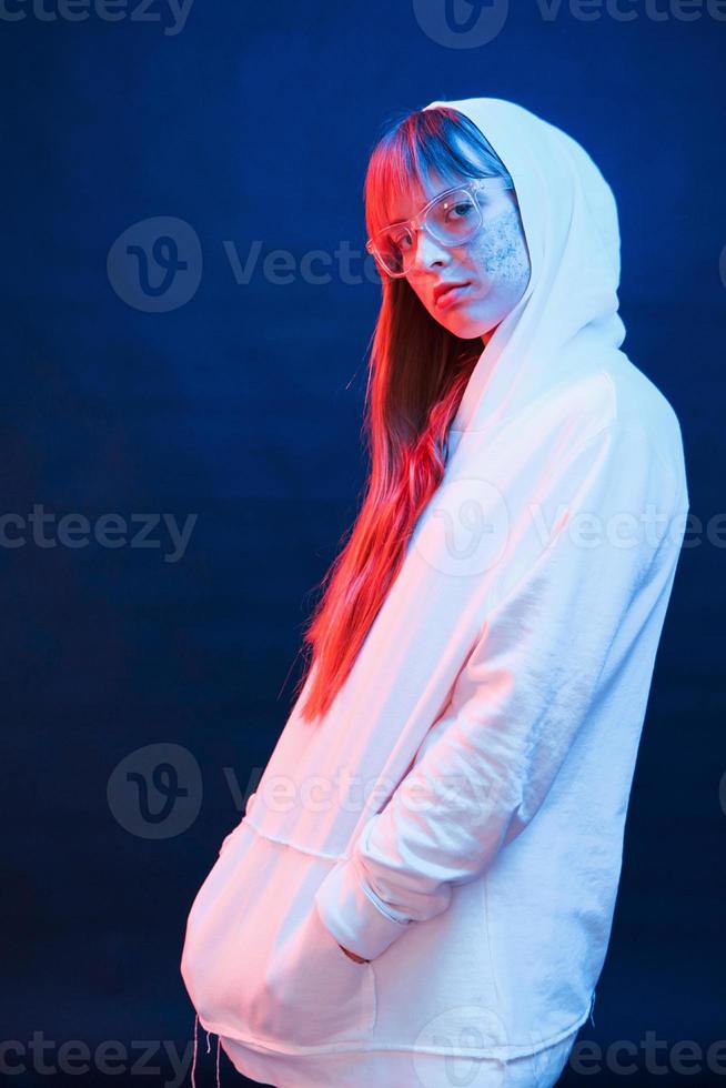Hood on the head. Studio shot in dark studio with neon light. Portrait of young girl photo