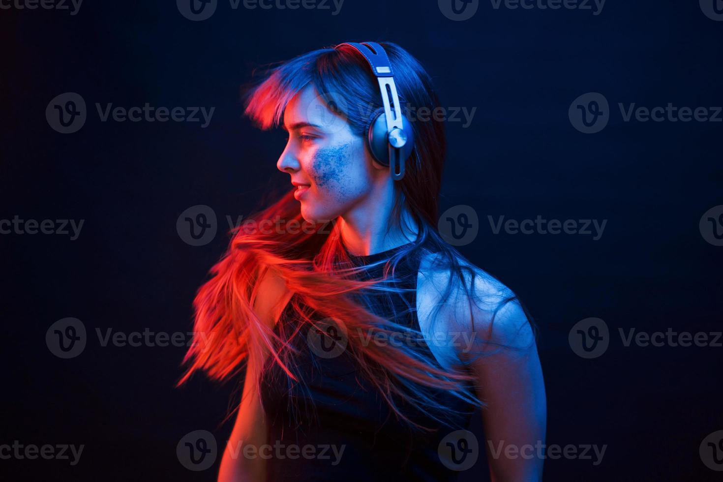 Photo im motion. Studio shot in dark studio with neon light. Portrait of young girl