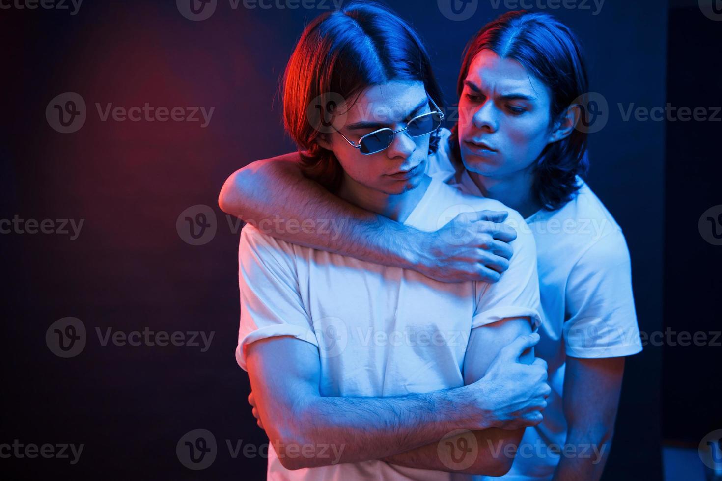 unidad del pueblo. retrato de hermanos gemelos. foto de estudio en estudio oscuro con luz de neón