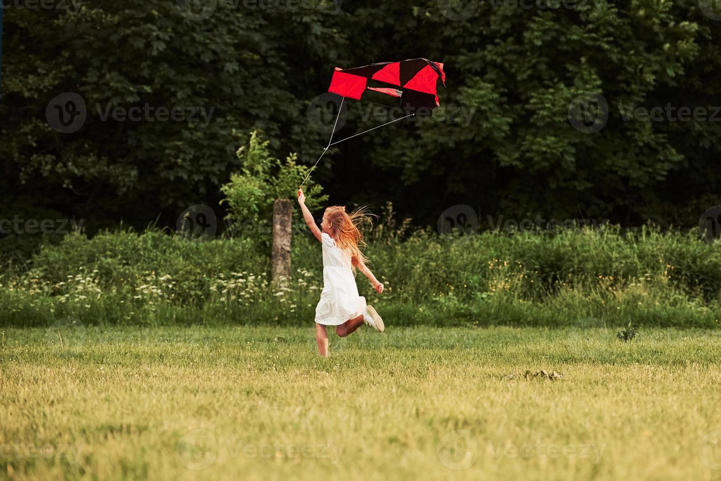 finalmente es verano. chica feliz vestida de blanco diviértete con cometa en el campo. Hermosa naturaleza foto