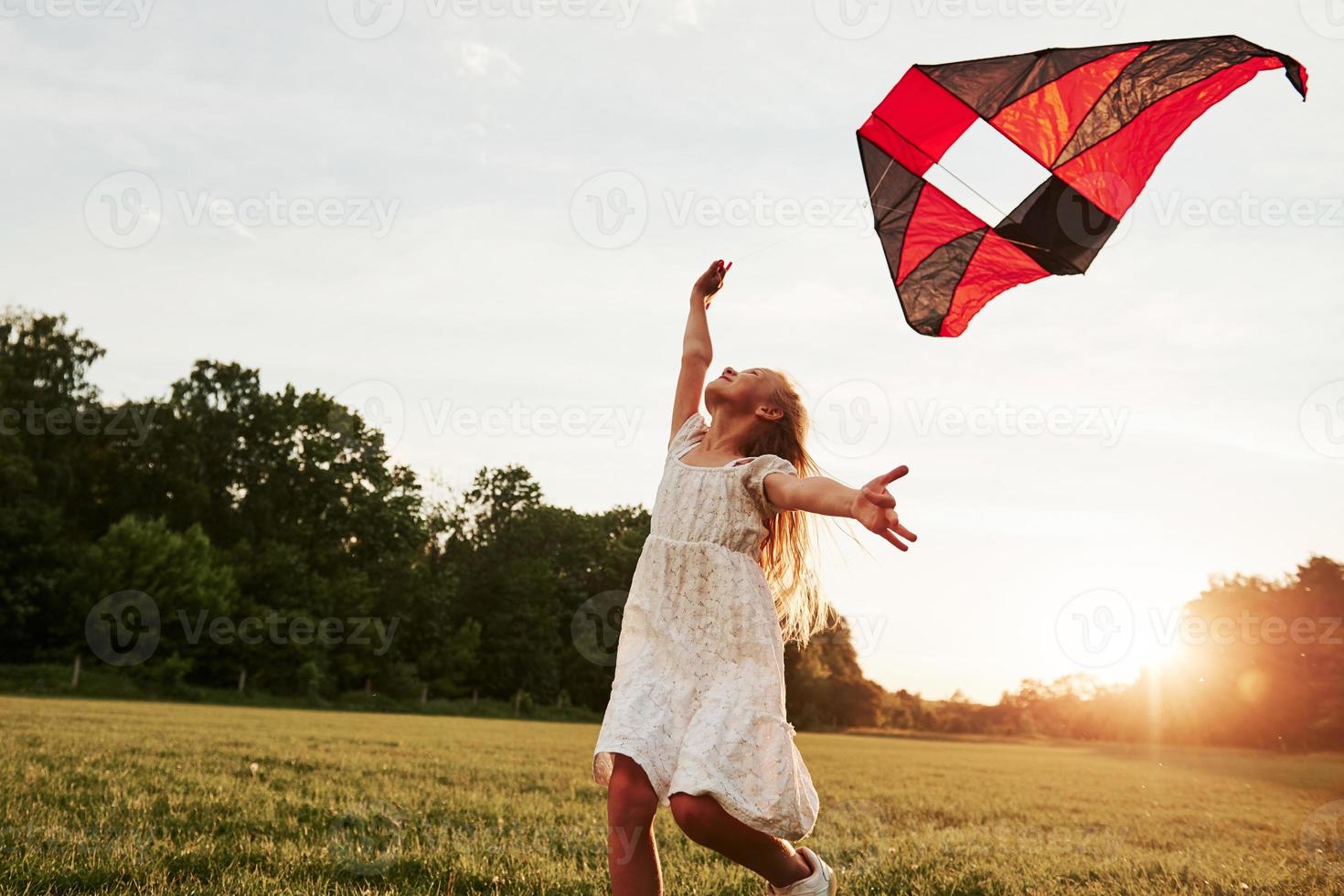 Feeling freedom. Happy girl in white clothes have fun with kite in the field. Beautiful nature photo