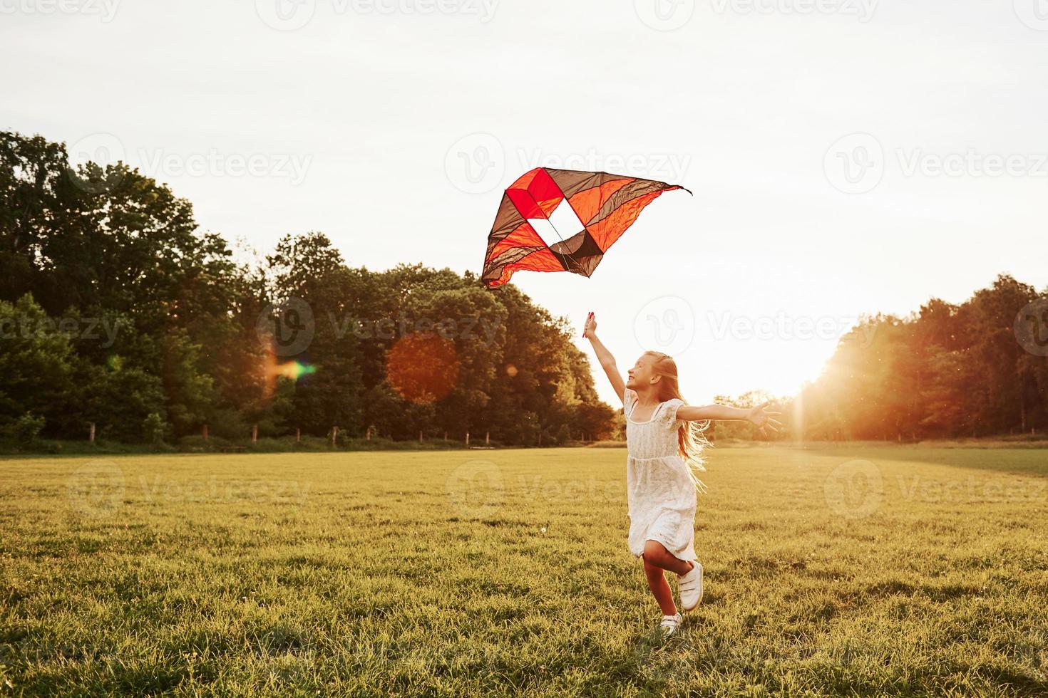 una sola persona chica feliz vestida de blanco diviértete con cometa en el campo. Hermosa naturaleza foto