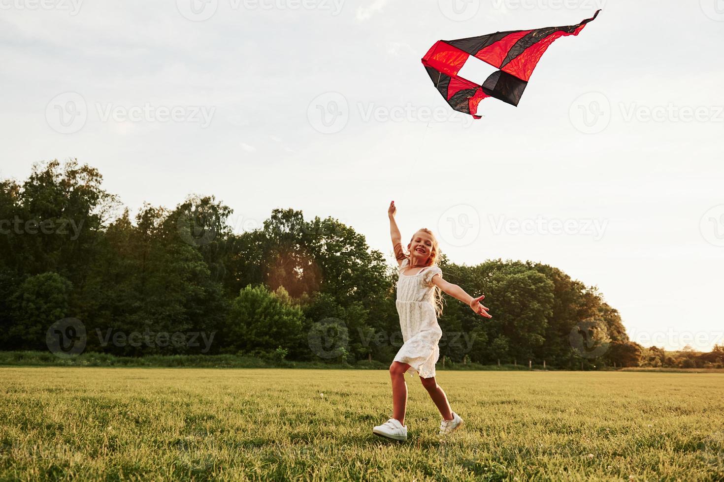 Come joing me. Happy girl in white clothes have fun with kite in the field. Beautiful nature photo