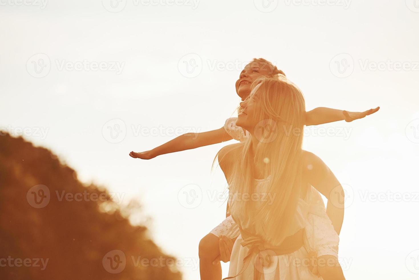 Imagine that you flying. Mother and daughter enjoying weekend together by walking outdoors in the field. Beautiful nature photo