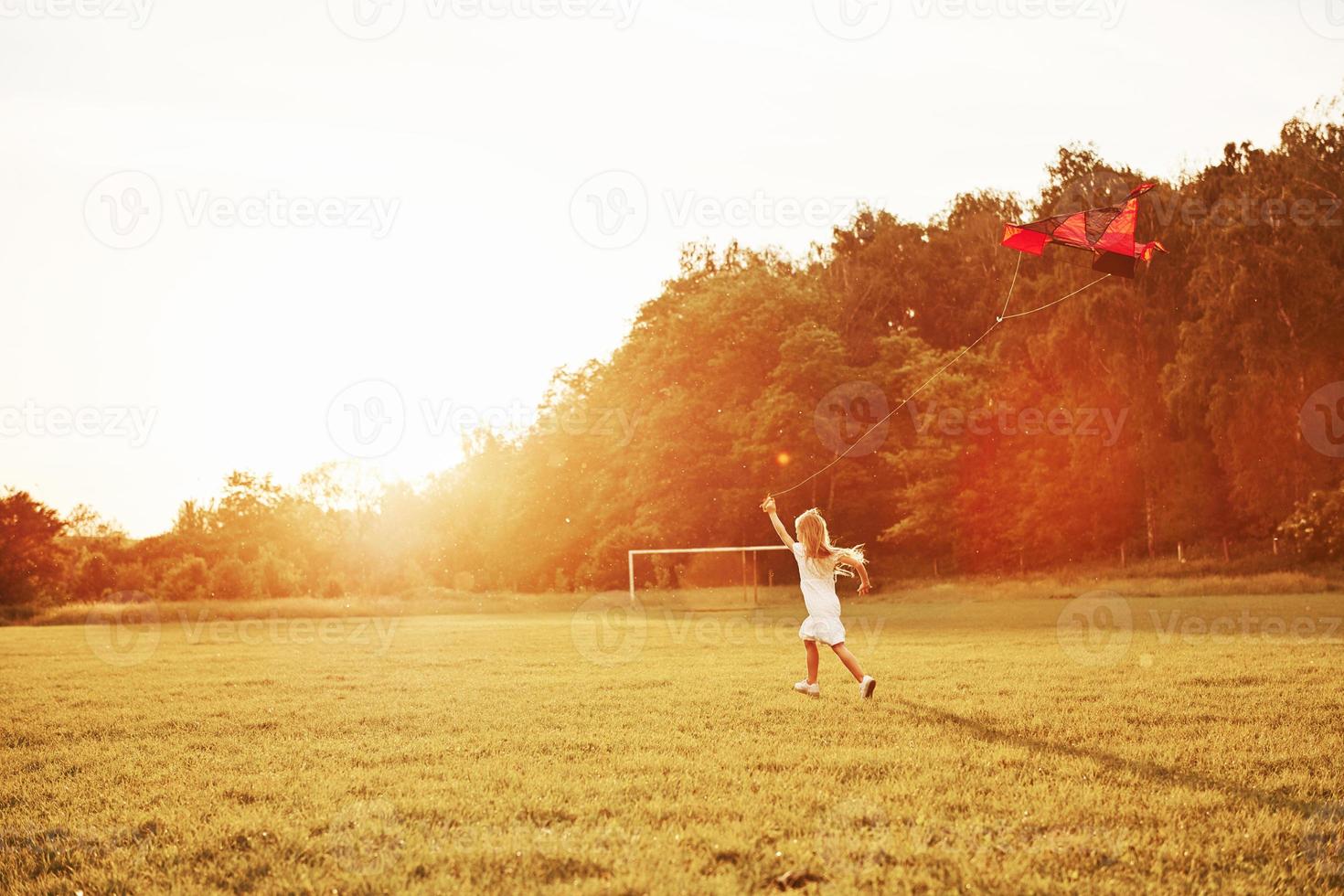 Lots of space to run. Happy girl in white clothes have fun with kite in the field. Beautiful nature photo