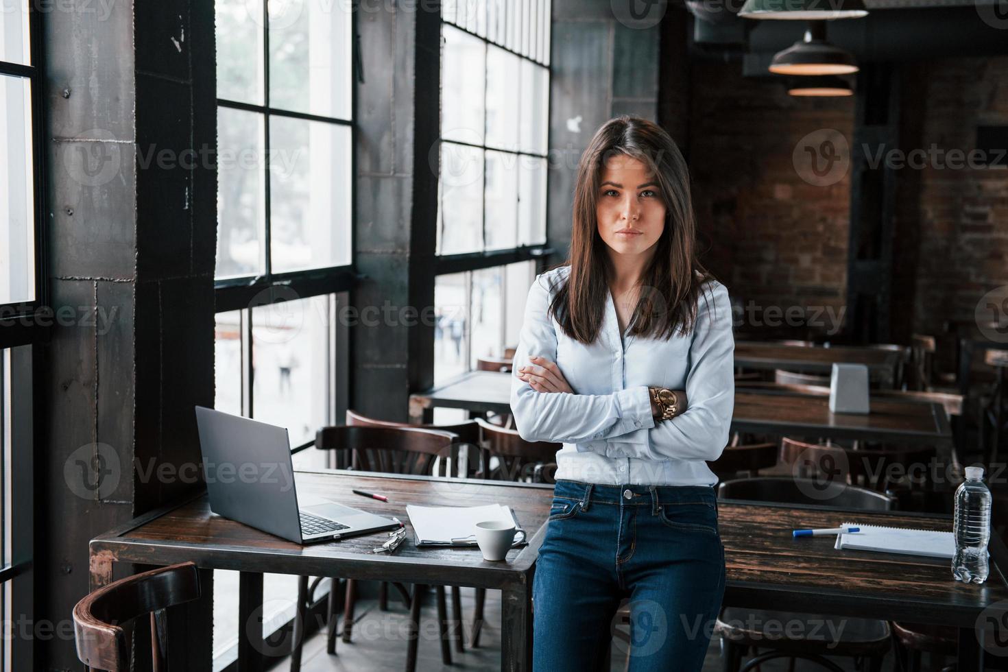 Serious manager. Businesswoman in official clothes is indoors in cafe at daytime photo