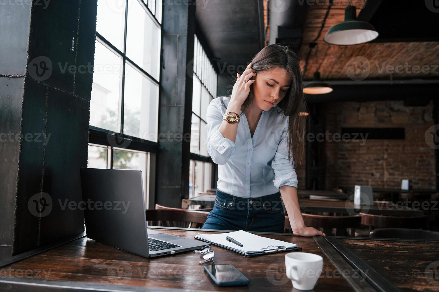 Need to be sure if everything is perfect in my report. Businesswoman in official clothes is indoors in cafe at daytime photo