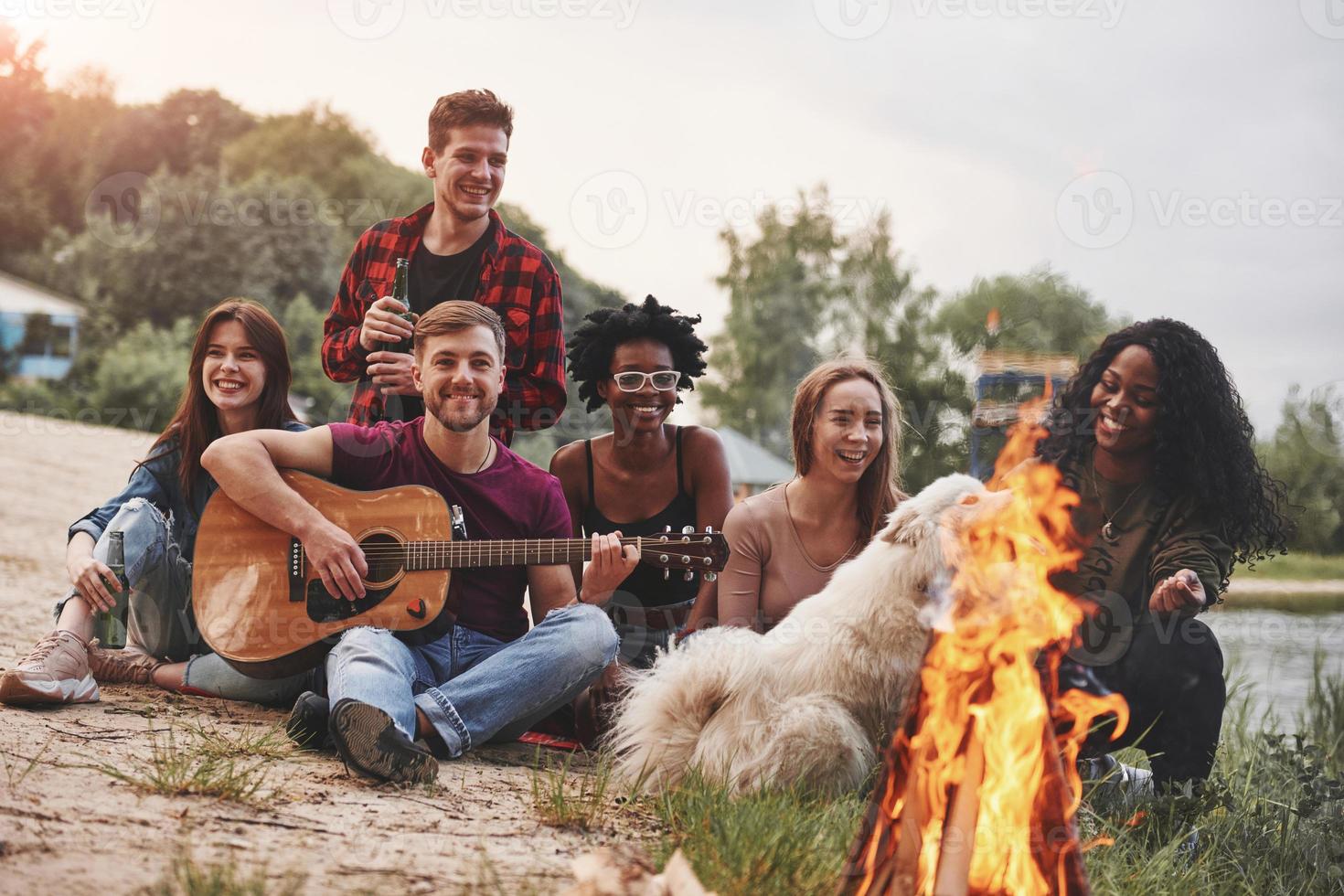 At sunset time. Group of people have picnic on the beach. Friends have fun at weekend photo