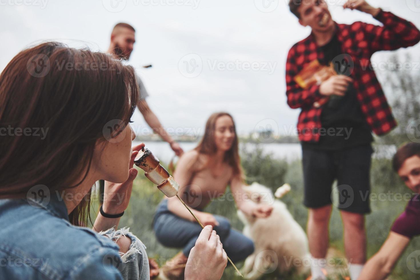 Focused photo. Group of people have picnic on the beach. Friends have fun at weekend time photo