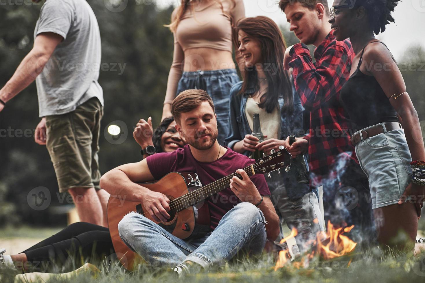 Youth style clothes. Group of people have picnic on the beach. Friends have fun at weekend time photo