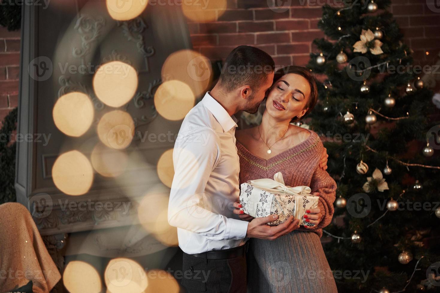 Conception of holidays. Christmas gift for the woman. Gentleman in classic suit gives his wife the present photo