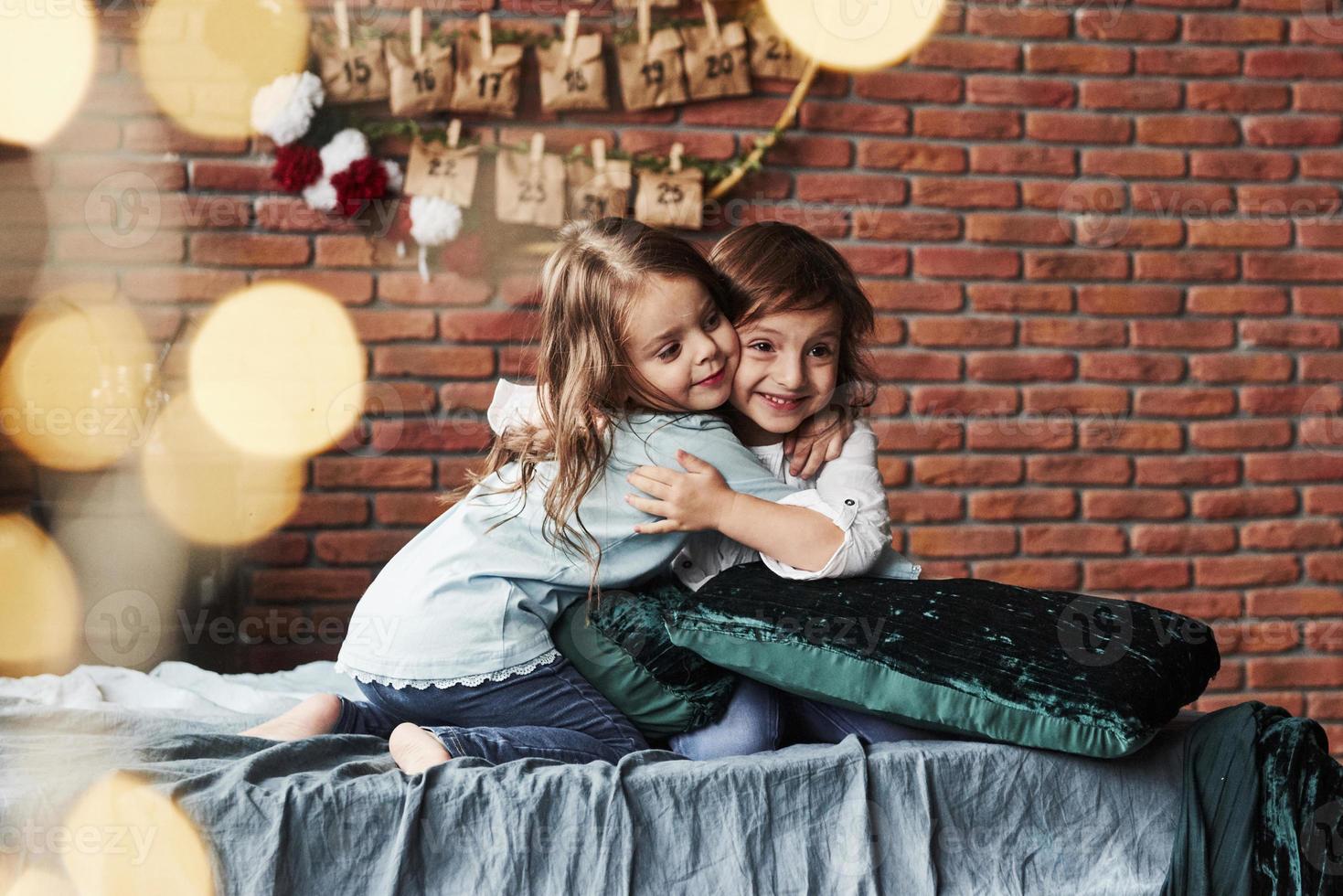 True friendship. Little girls having fun on the bed with holiday interior at the background photo