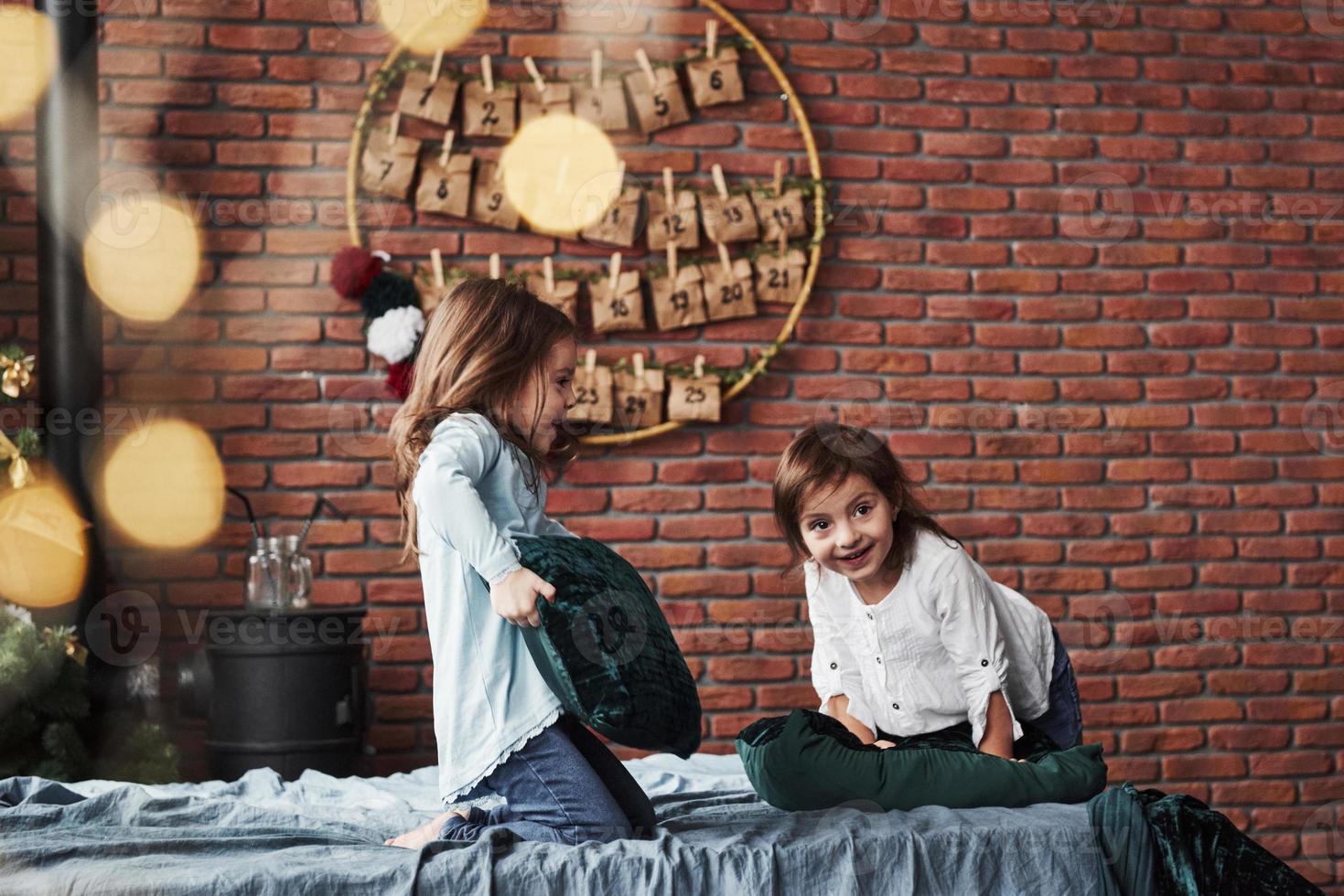 Little girls having fun on the bed with holiday interior at the background photo