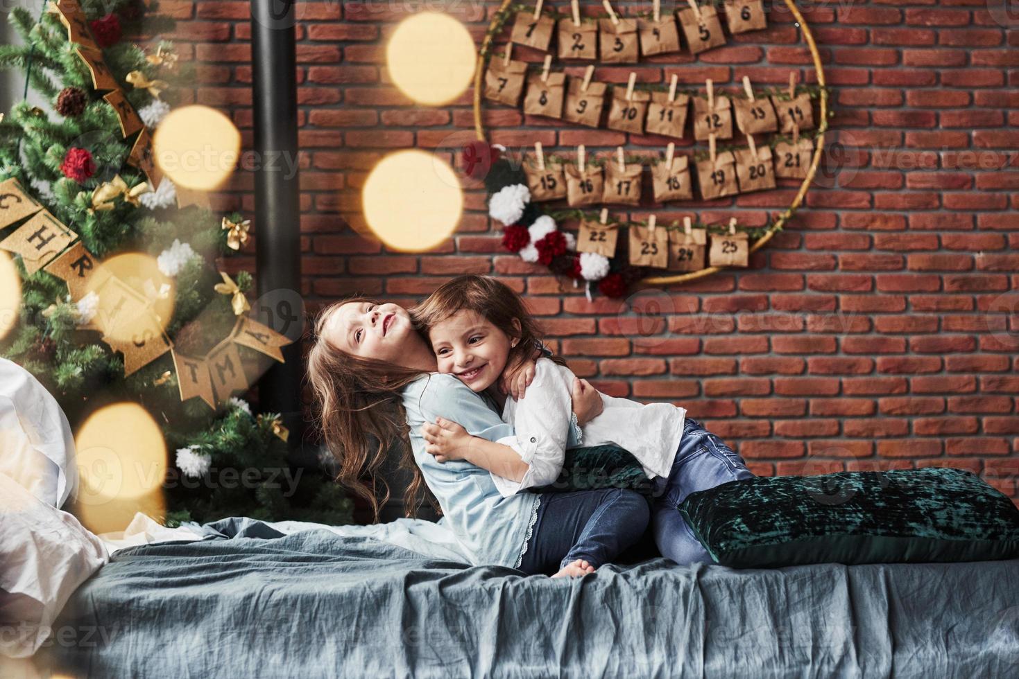 Children finally met each other. Little girls having fun on the bed with holiday interior at the background photo