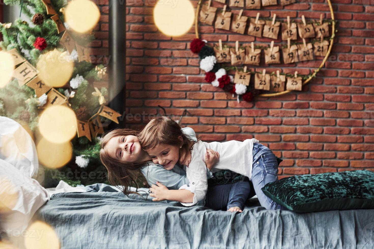 So cute. Little girls having fun on the bed with holiday interior at the background photo