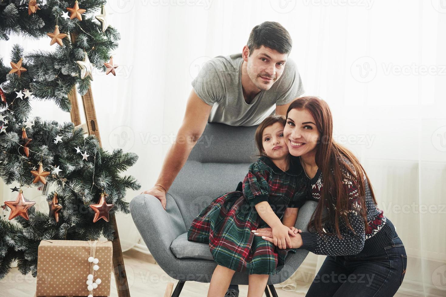 Holidays together. Portrait of the happy family on the new year celebration. Girl sits on the chair photo