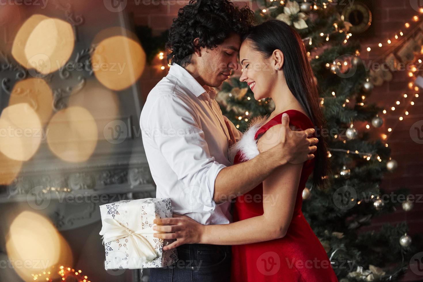 la chica sostiene una caja de regalo blanca. baile de noche de año nuevo. encantadora hermosa pareja pasando tiempo juntos foto