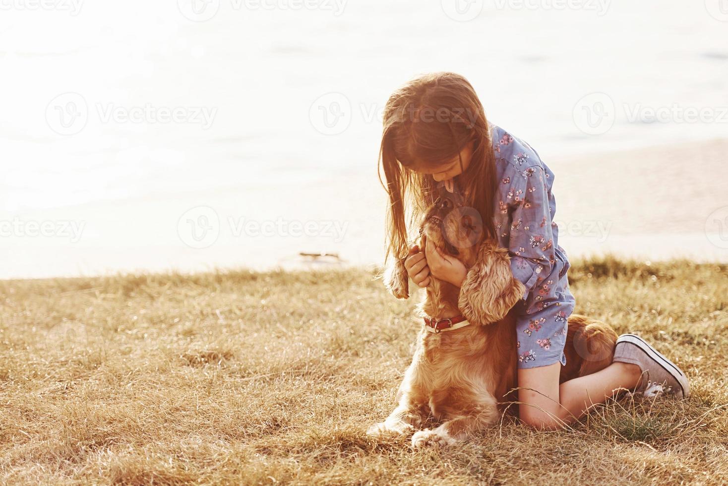 Playing with pet. Cute little girl have a walk with her dog outdoors at sunny day photo