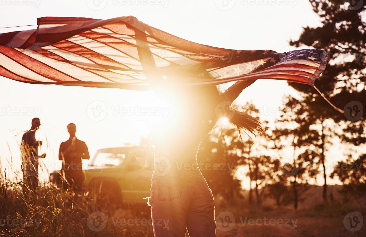 Friends have nice weekend outdoors near theirs green car with USA flag photo