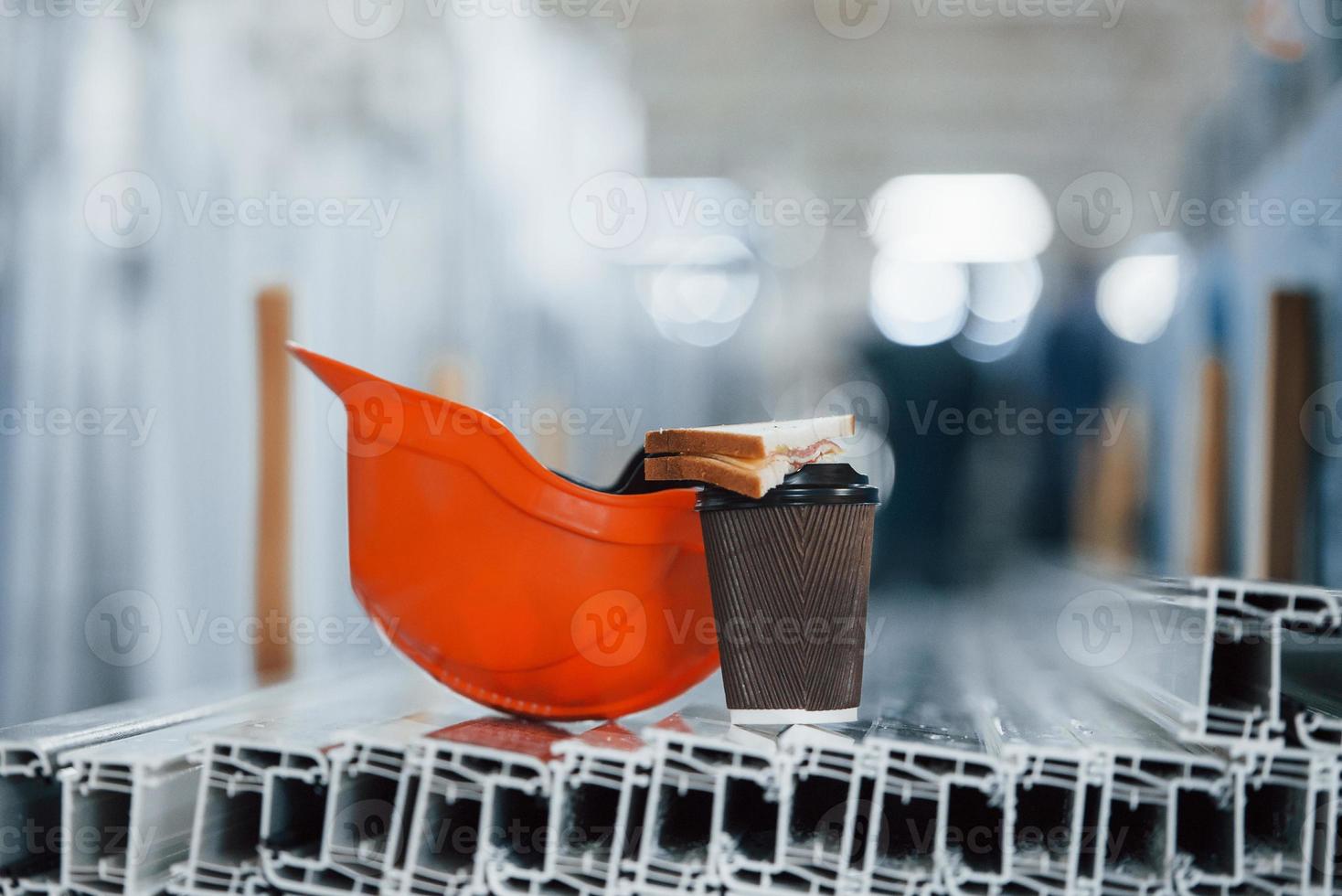 el pan está en la copa con la bebida. casco naranja sobre objetos en la fábrica. nadie. concepción de la hora del almuerzo foto