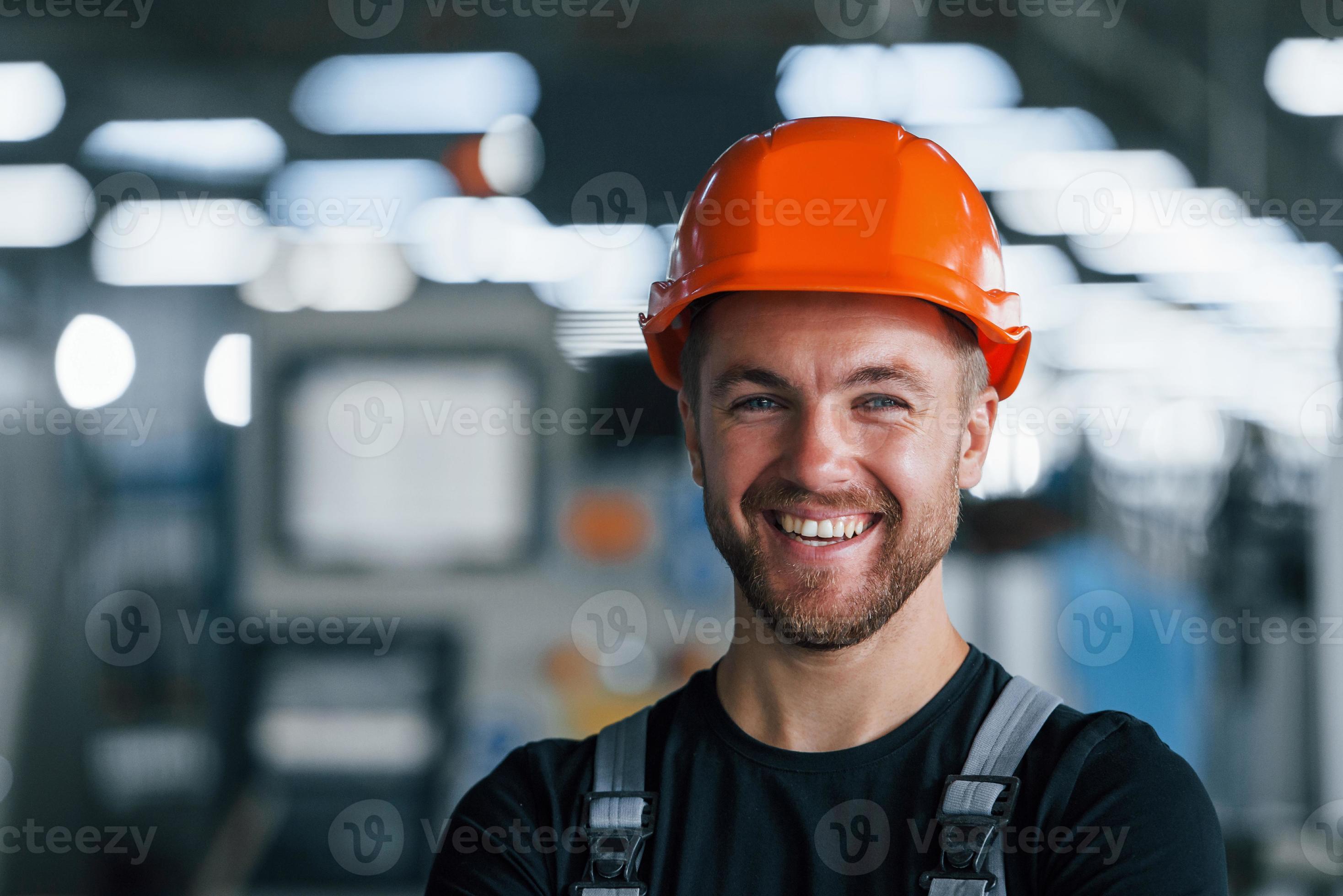 Smiling and happy employee. Portrait of industrial worker indoors in factory. Young technician