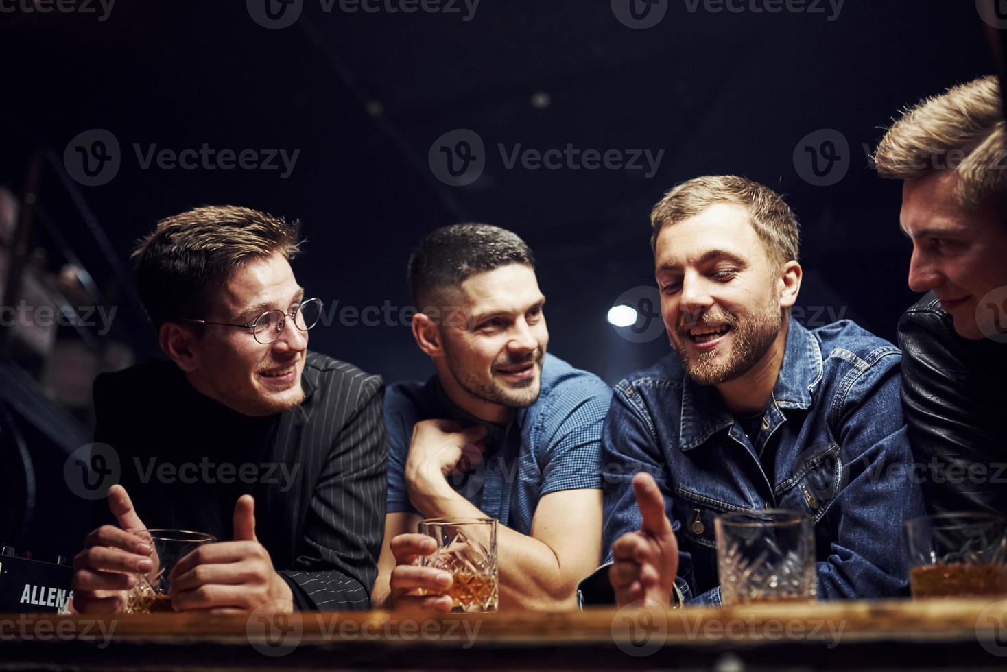 Front view. Friends resting in the pub with alcohol in hands. Having conversation photo