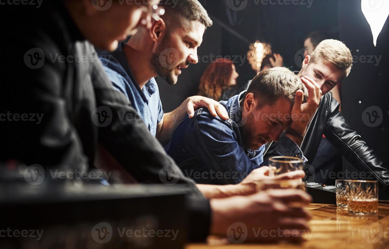 Guy feels awful. Friends resting in the pub with alcohol in hands. Having conversation photo