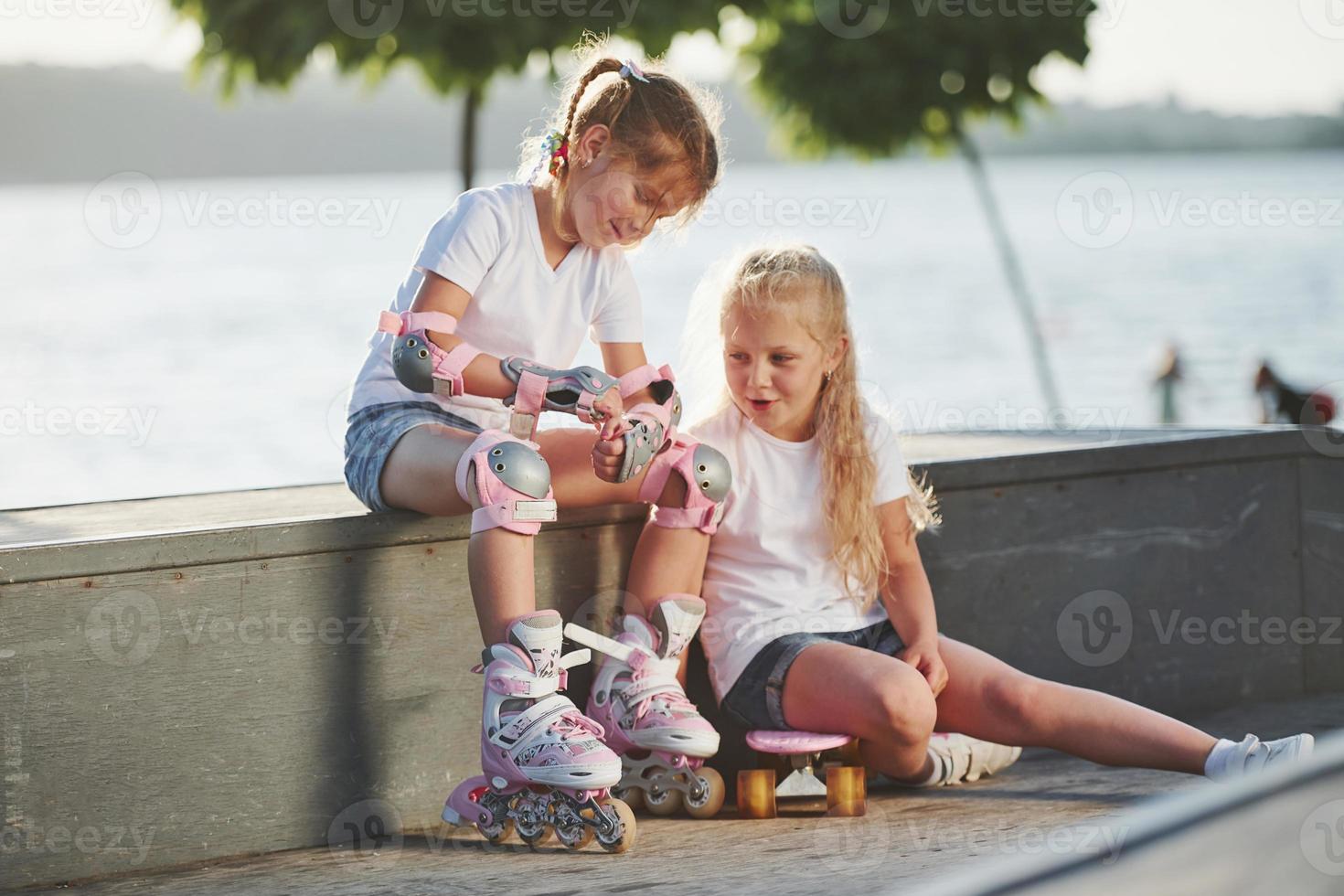 hablando unos con otros. en la rampa para los deportes extremos. dos niñas pequeñas con patines al aire libre se divierten foto