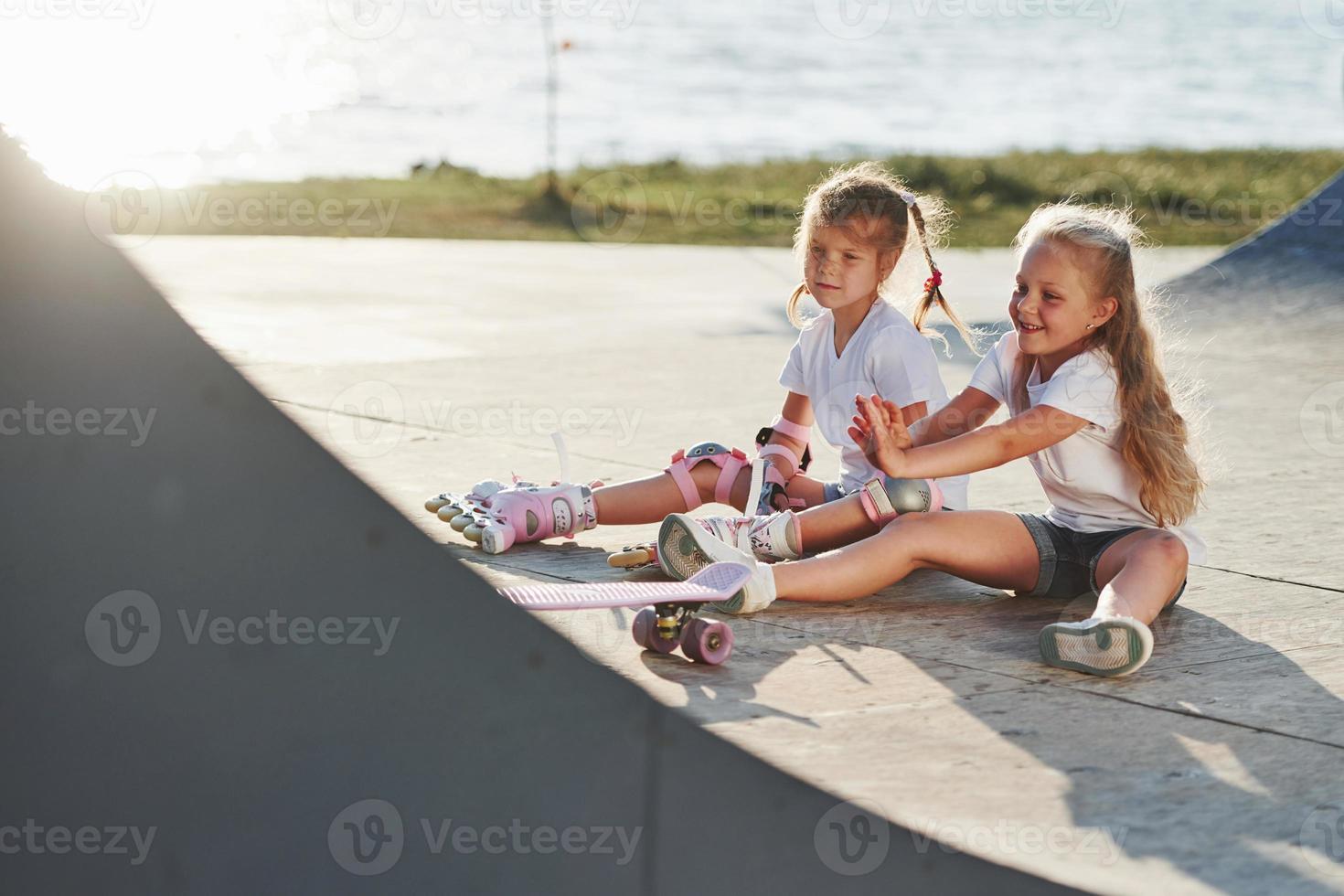 Relaxing and have conversation. On the ramp for extreme sports. Two little girls with roller skates outdoors have fun photo