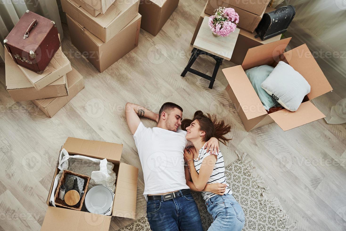 Taking a rest. Lying down on the floor. Cheerful young couple in their new apartment. Conception of moving photo