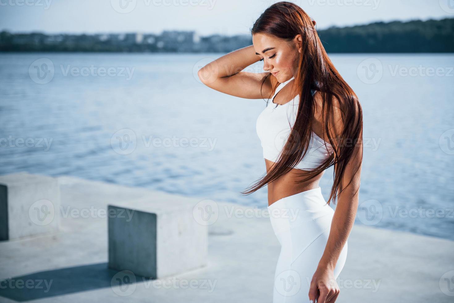 Fitness woman having a rest near the lake at daytime. Beautiful sunlight photo