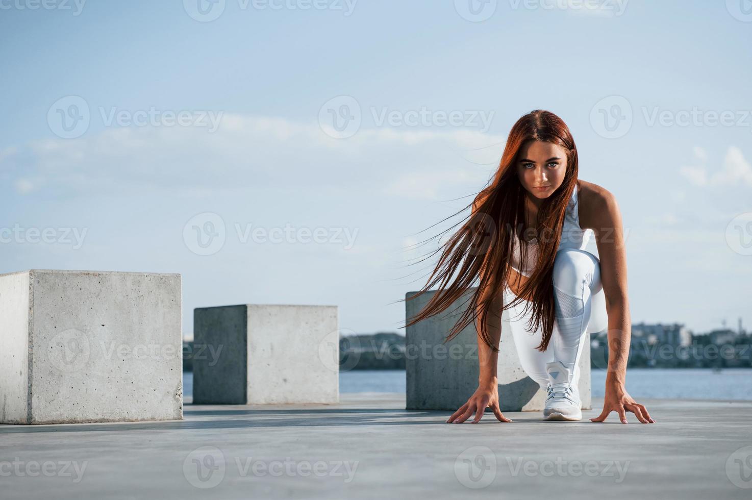 Ready for the run. Shot of sportive woman doing fitness exercises near the lake at daytime photo