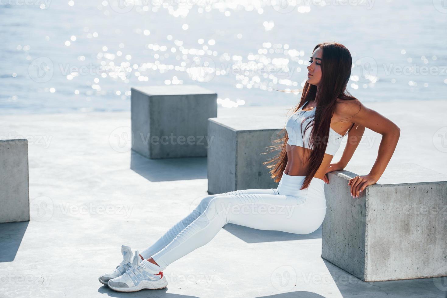 Exercises for hands. Shot of sportive woman doing fitness near the lake at daytime photo