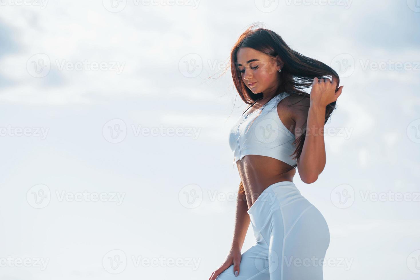 Posing for the camera. Young fitness woman with slim body type is outdoors photo