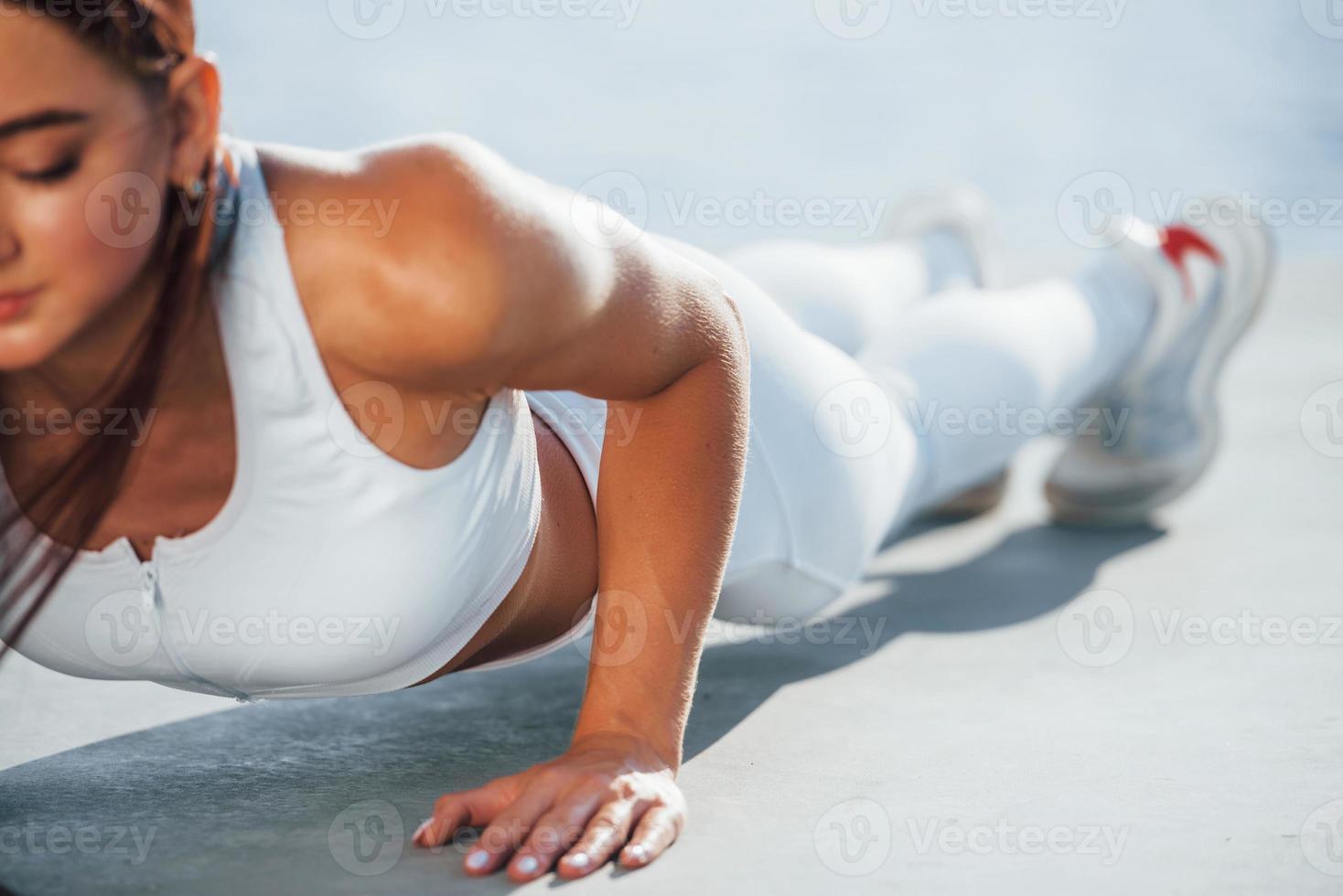Shot of sportive woman doing fitness exercises near the lake at daytime photo