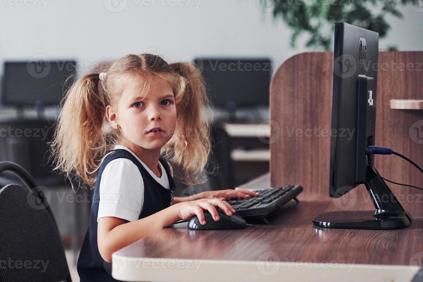 niña sentada junto a la computadora y buscando información foto