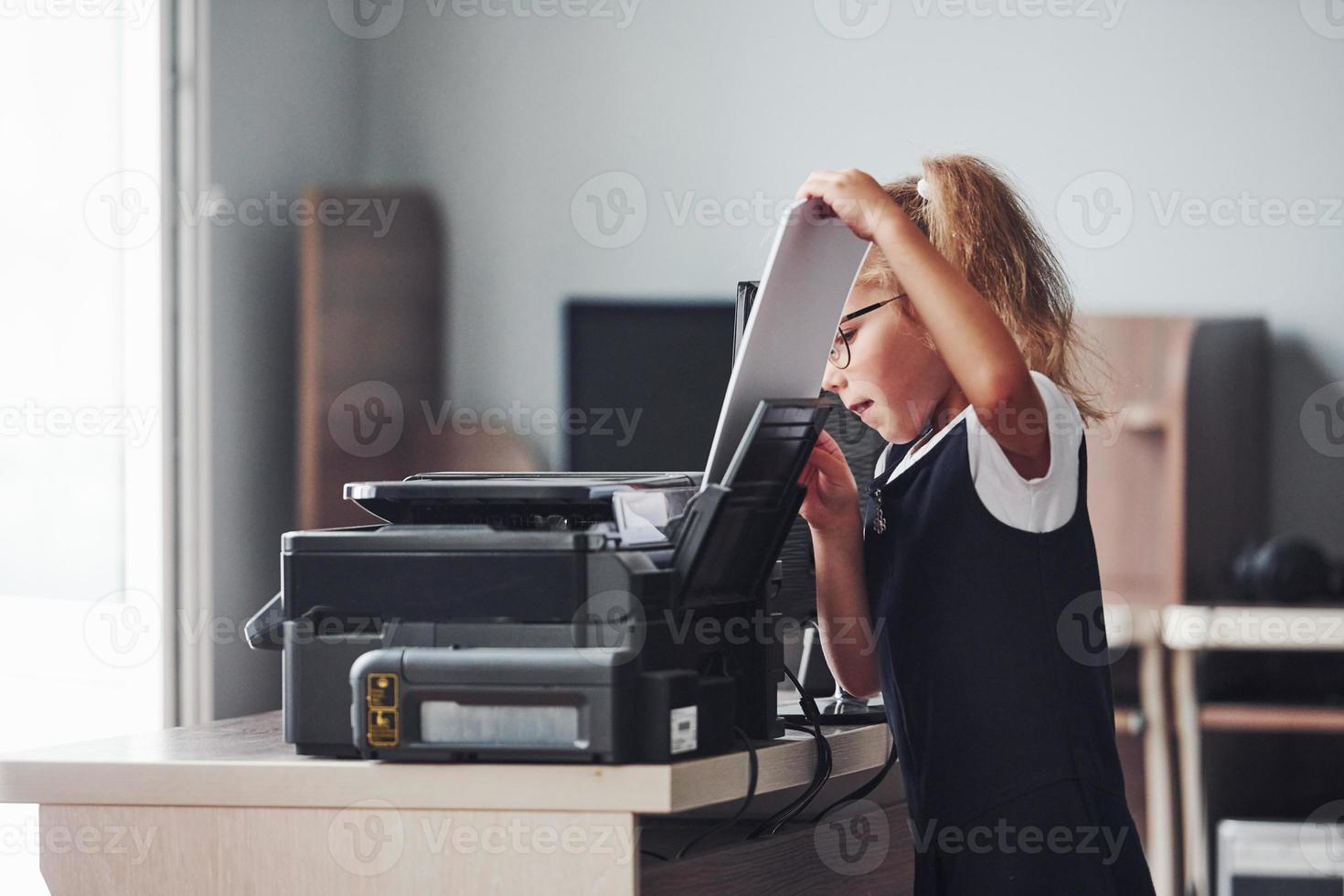 Working process. Girl holds paper and puts it into the printer photo