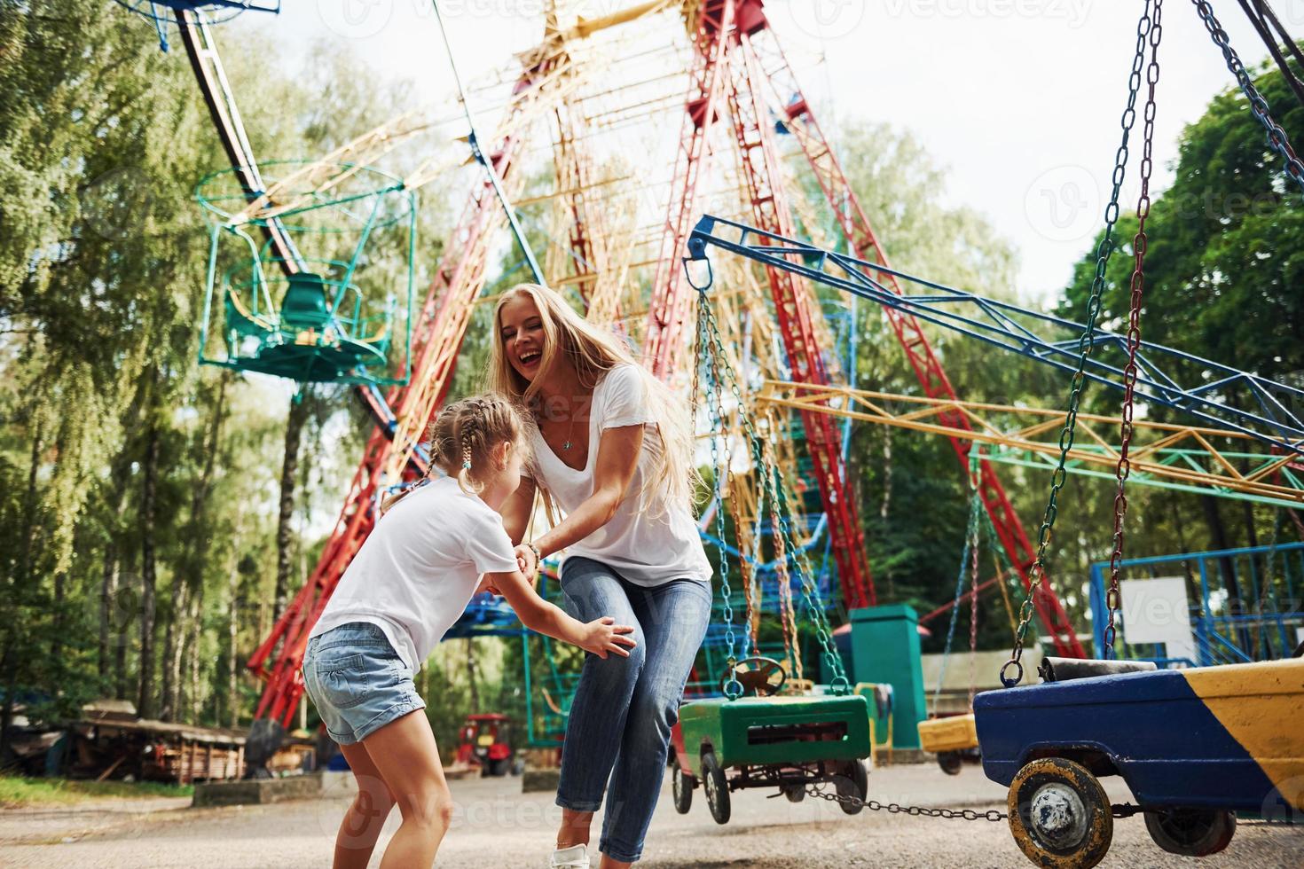 corriendo y jugando. niña alegre su madre se divierten juntos en el parque cerca de las atracciones foto