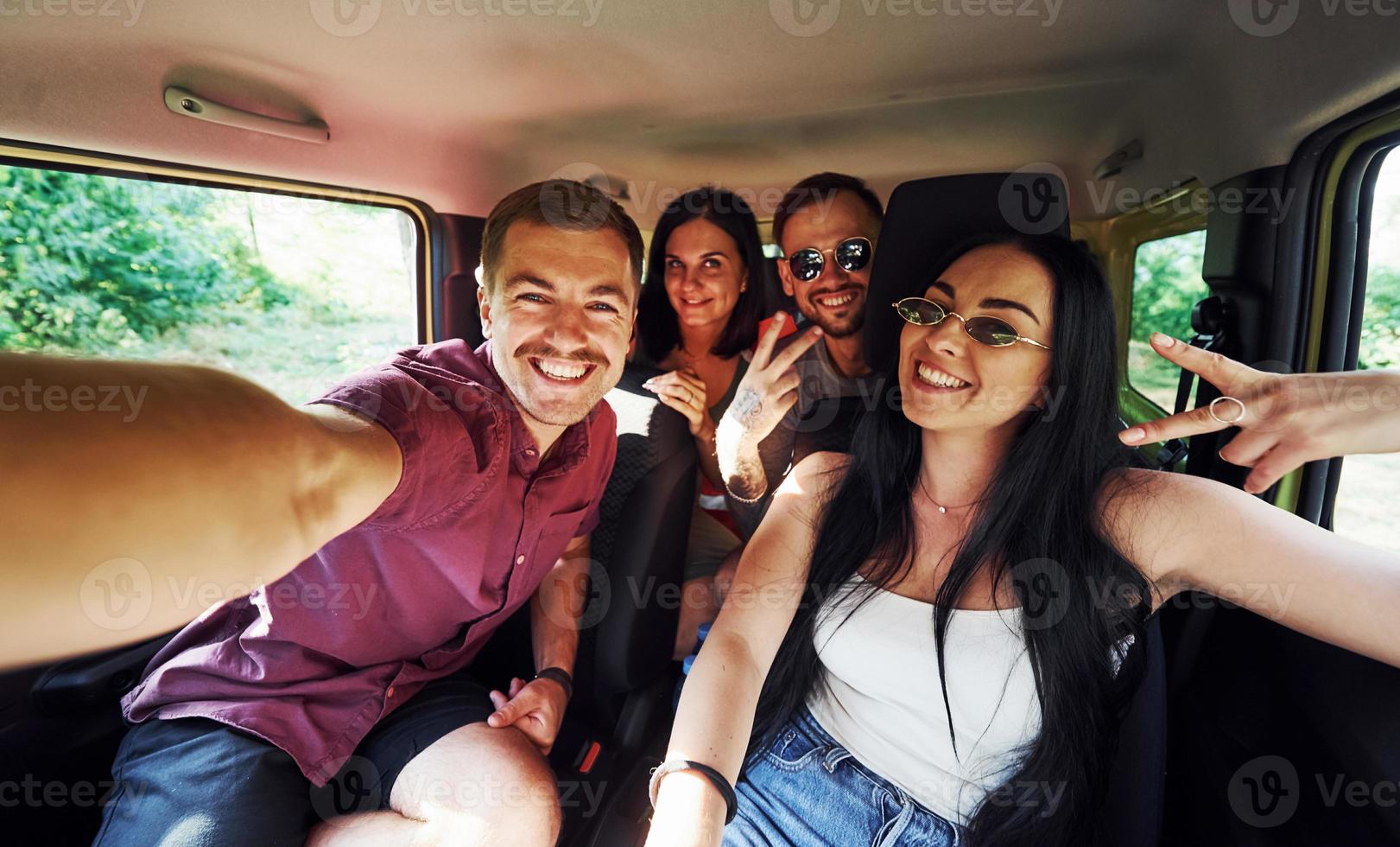 gente joven y alegre haciendo un selfie dentro de un auto. teniendo fin de semana foto