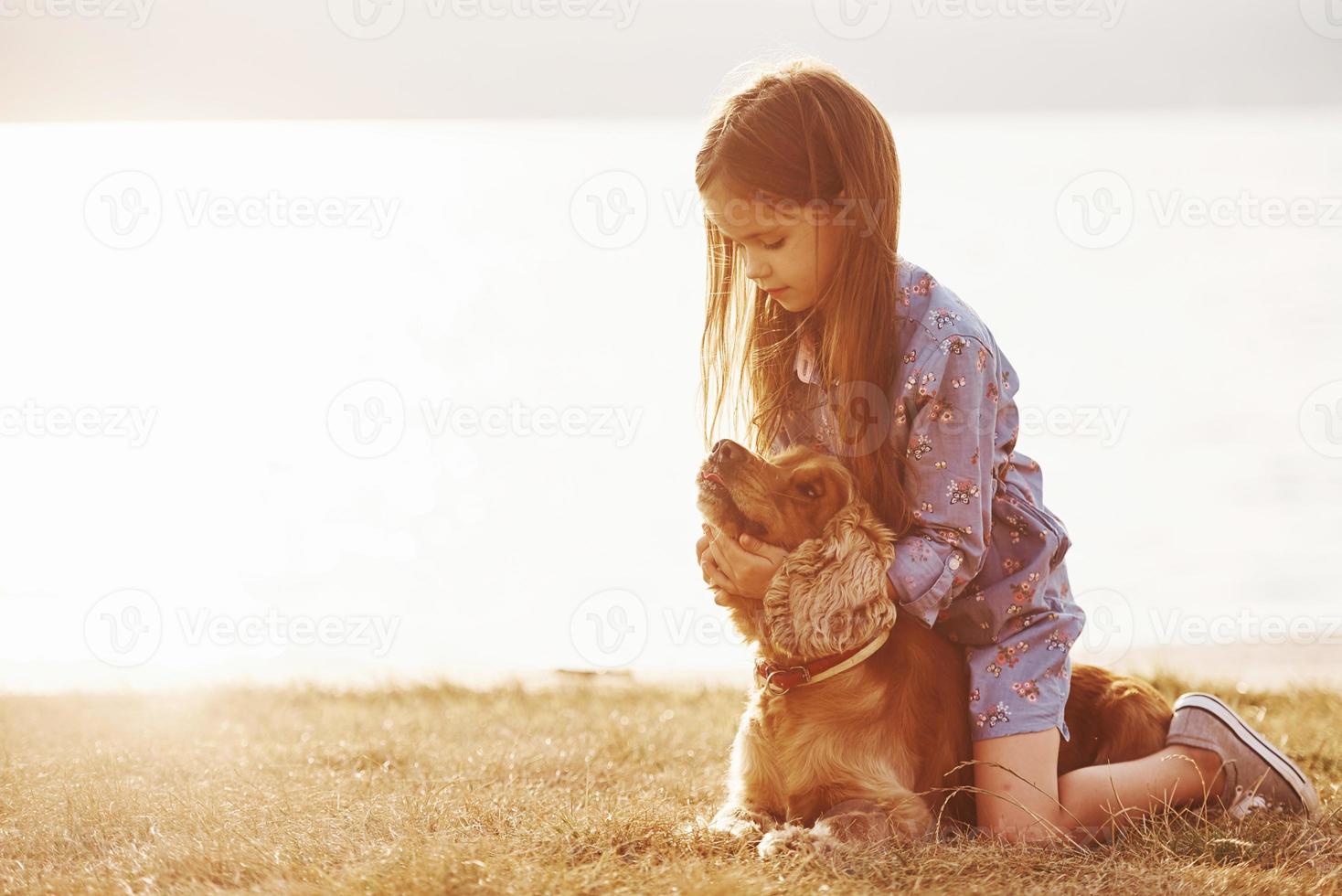 Playing with pet. Cute little girl have a walk with her dog outdoors at sunny day photo