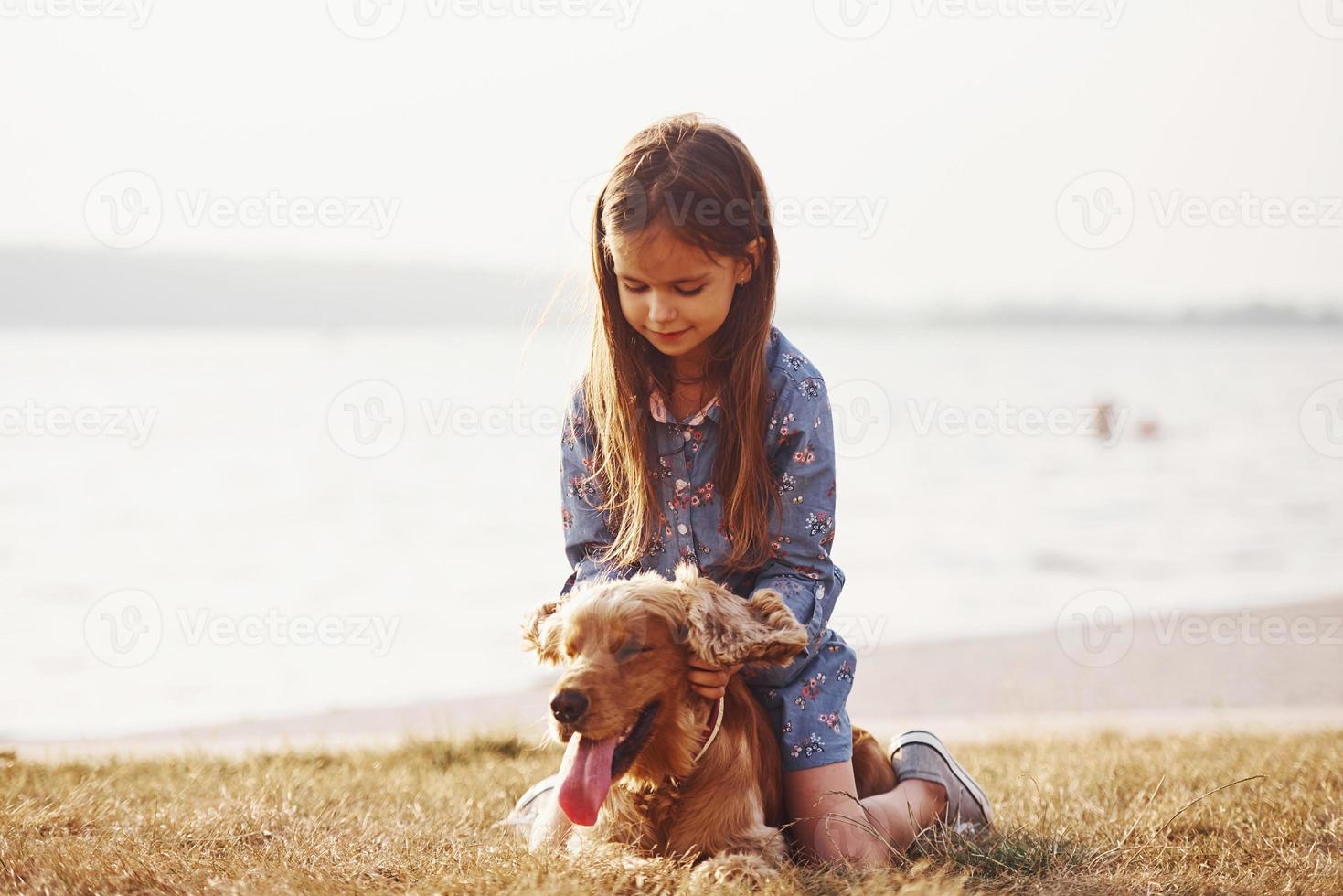 Playing with pet. Cute little girl have a walk with her dog outdoors at sunny day photo