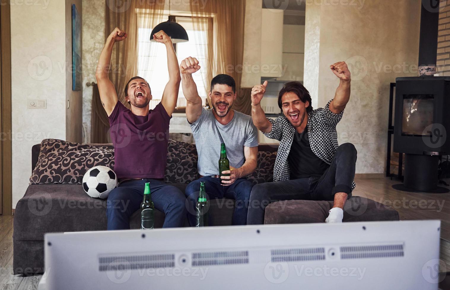It's a goal. Excited three friends watching soccer on TV at home together photo