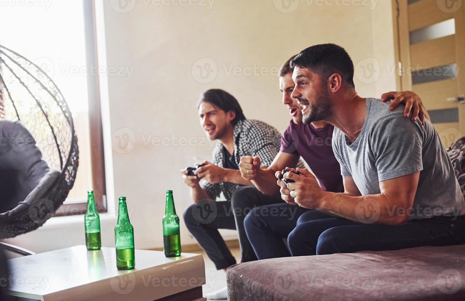 Group of friends have fun playing console game indoors at living room photo