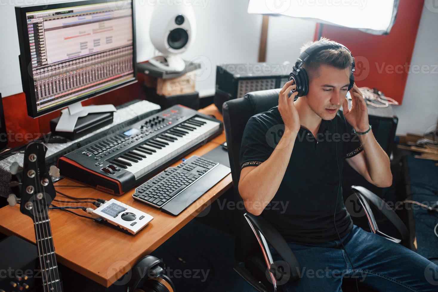Listening to the music. Sound engineer in headphones working and mixing indoors in the studio photo