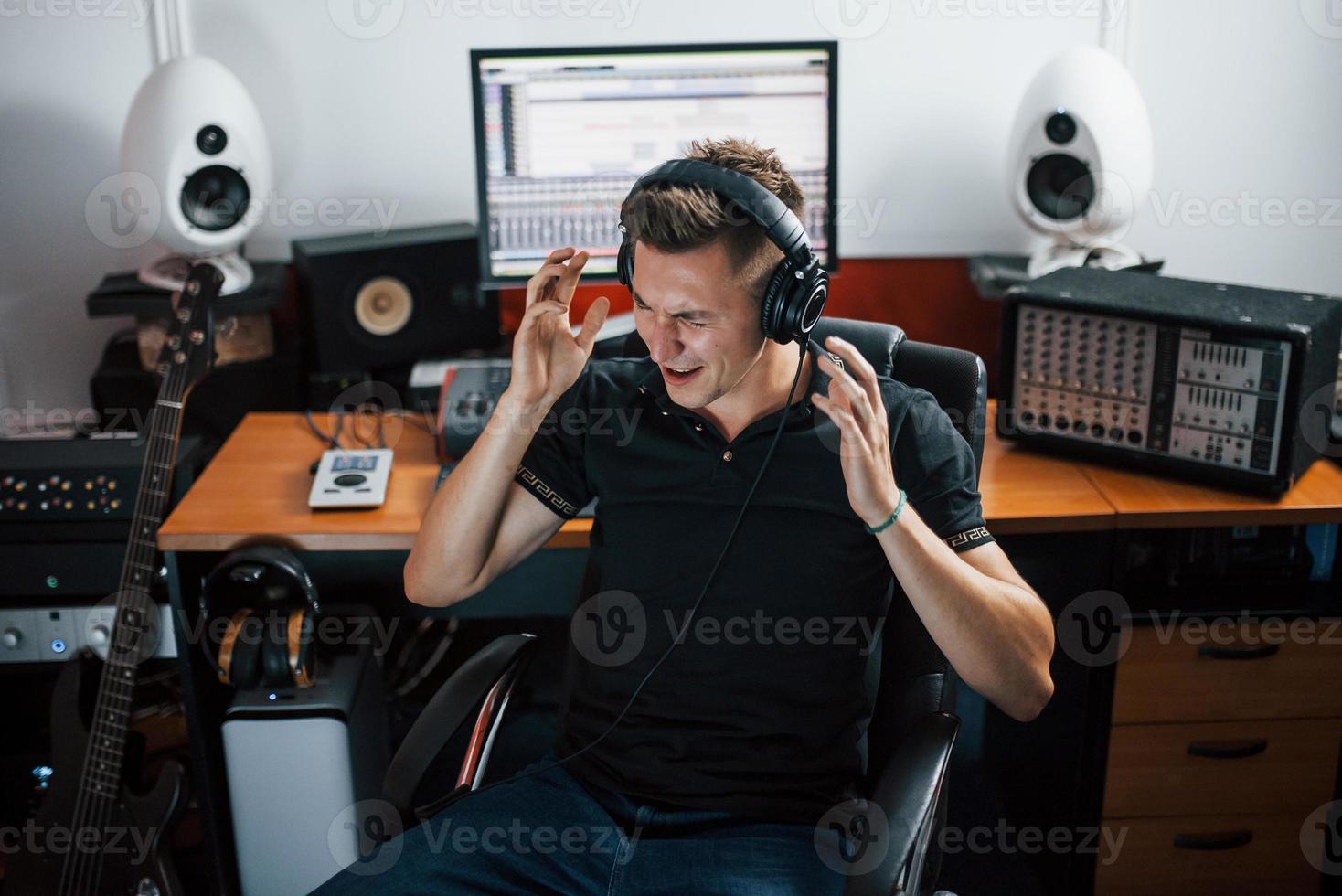 Satisfied with audio quality. Sound engineer in headphones working and mixing music indoors in the studio photo