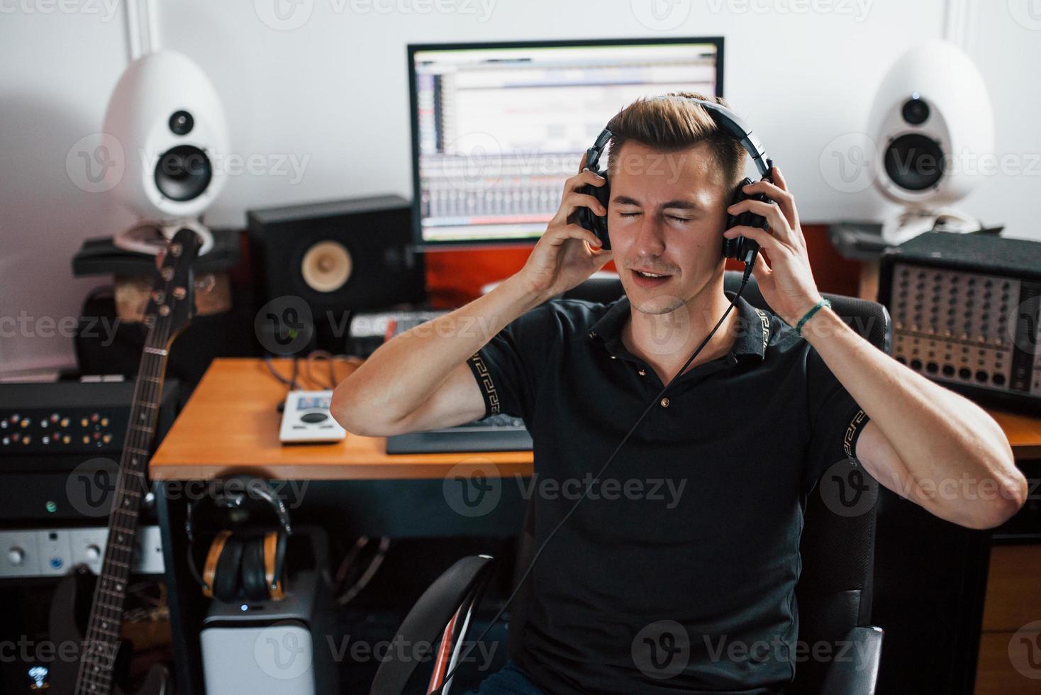 Satisfied with audio quality. Sound engineer in headphones working and mixing music indoors in the studio photo