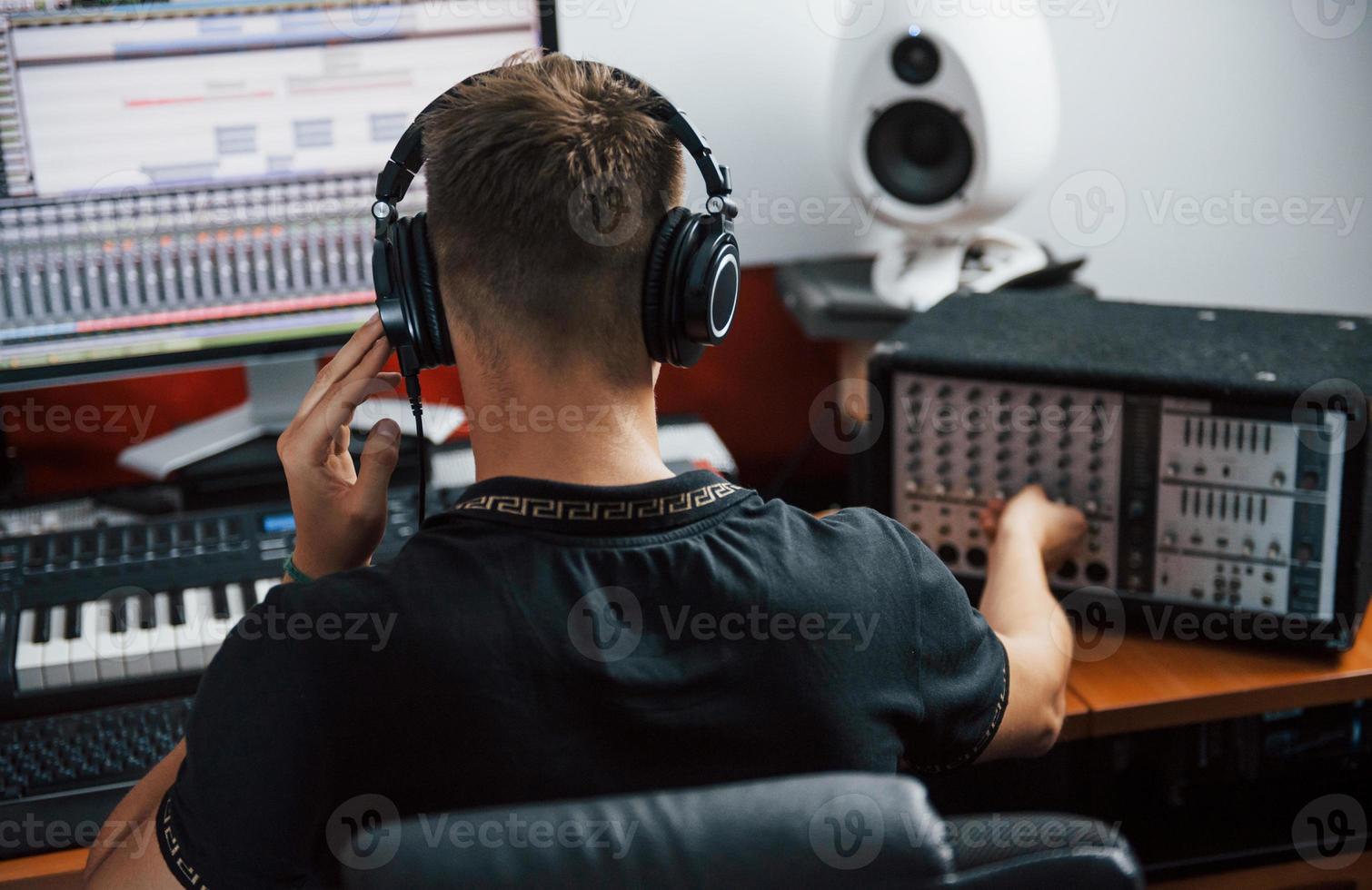 ingeniero de sonido en auriculares trabajando y mezclando música en interiores en el estudio foto