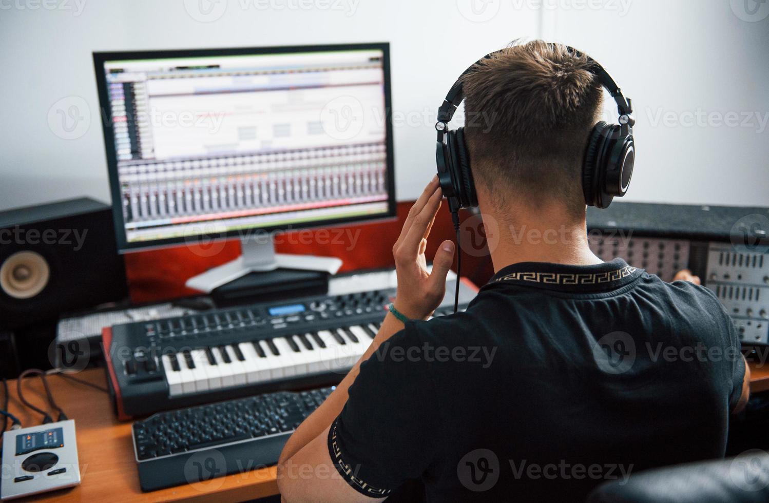 Sound engineer in headphones working and mixing music indoors in the studio photo