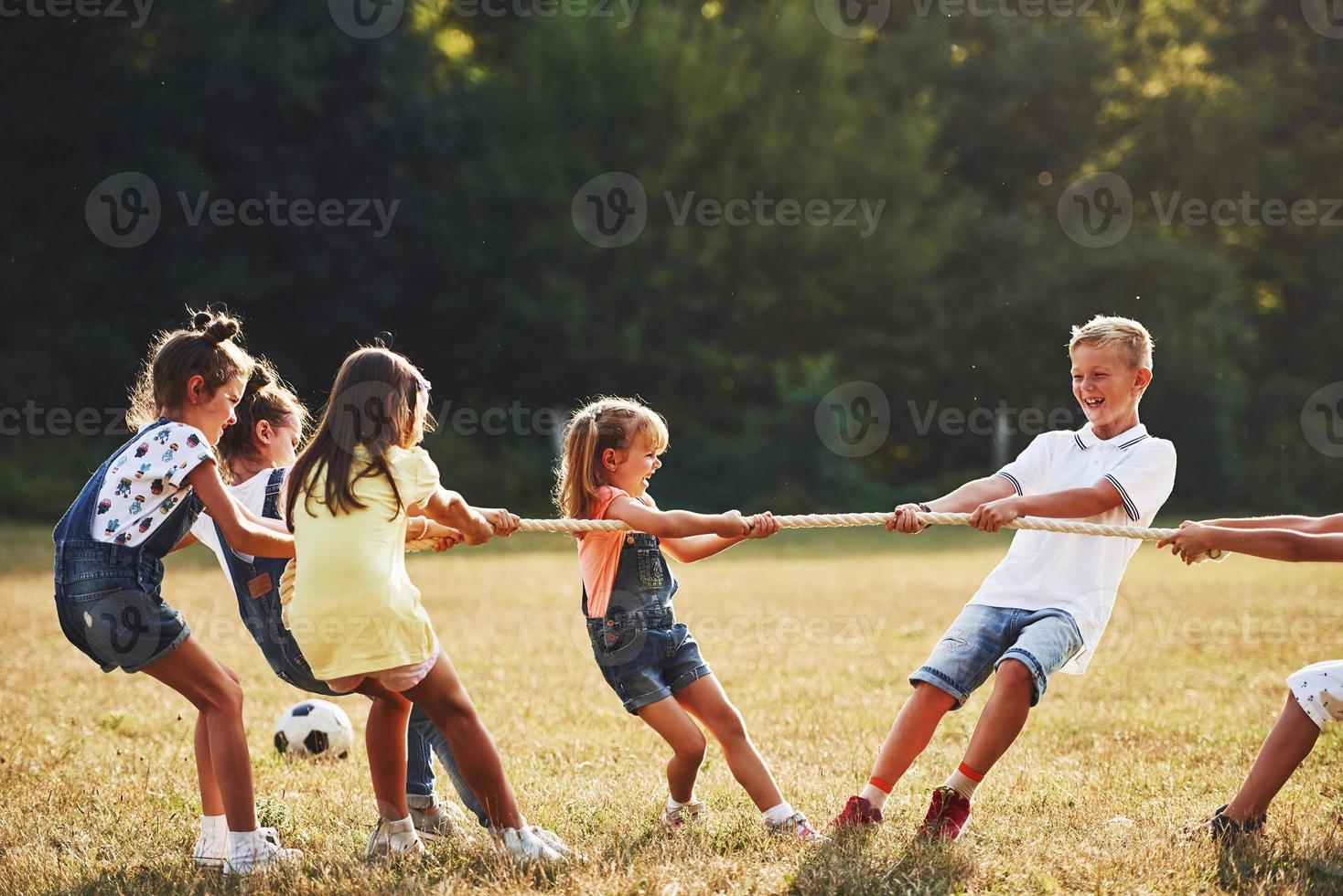 Kids playing tug of war game in the beautiful meadow at sunny day photo